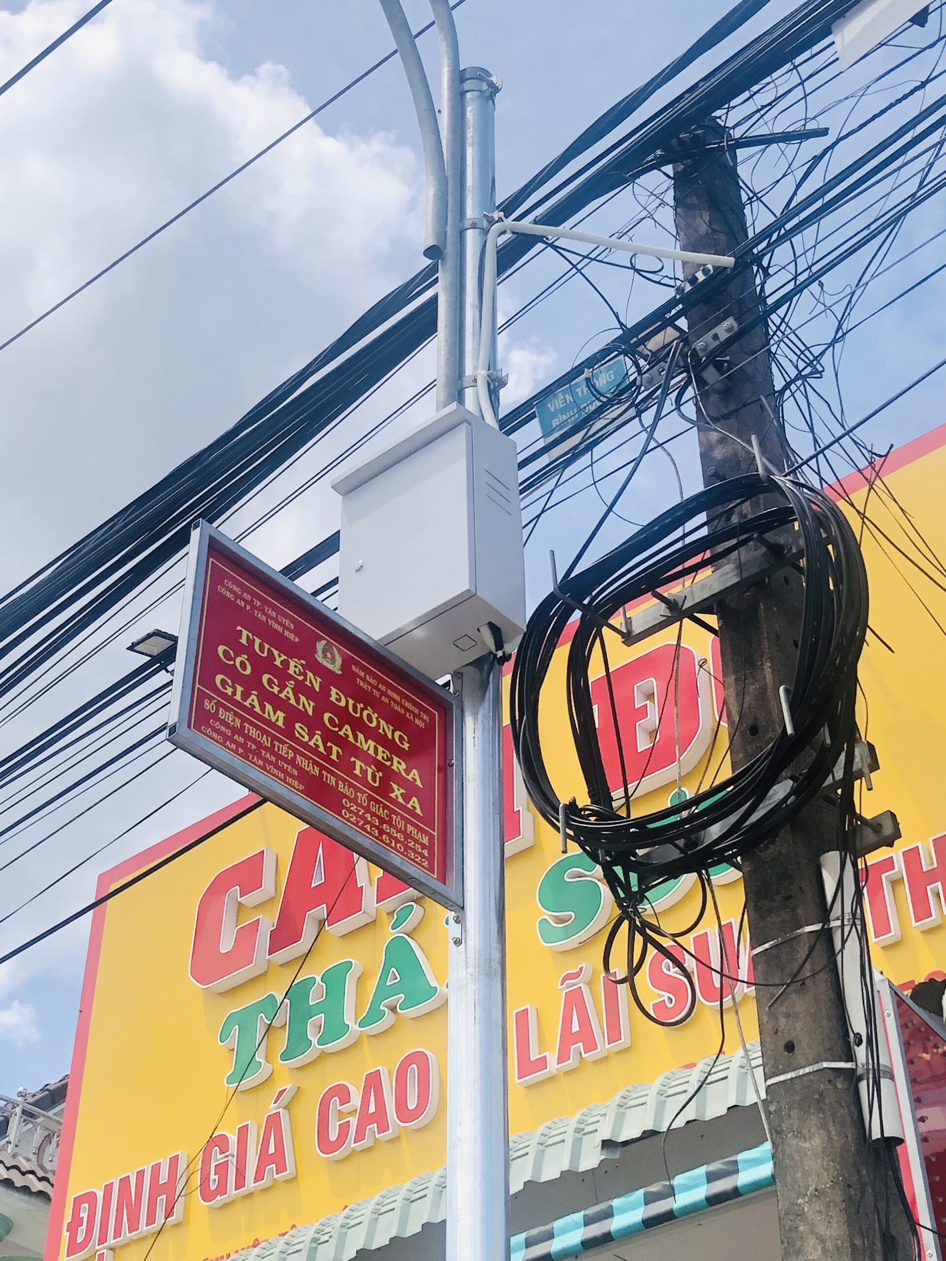 Cận cảnh camera và biển báo giám sát lắp gần cửa hàng cầm đồ.