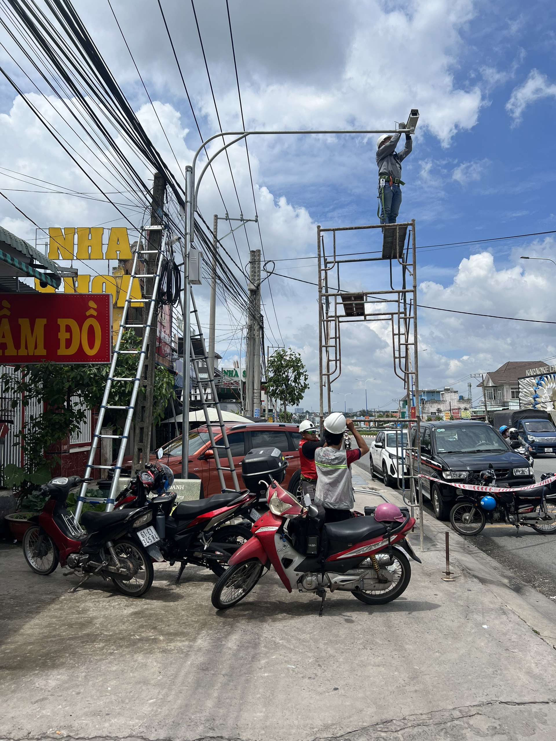 KTV đứng trên giàn giáo lắp đặt cần camera phía trên tuyến đường.